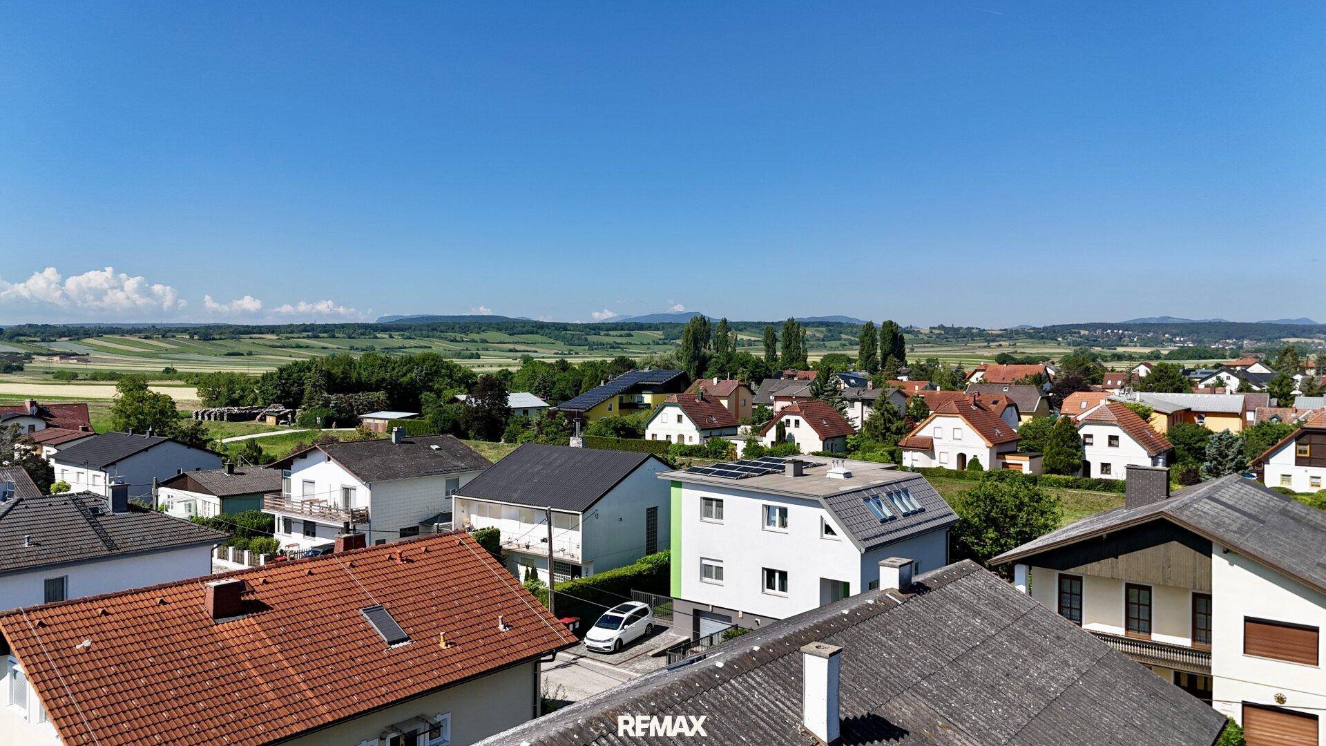 Weitläufige Luftaufnahme der Wohngegend mit grünen Hügeln im Hintergrund.