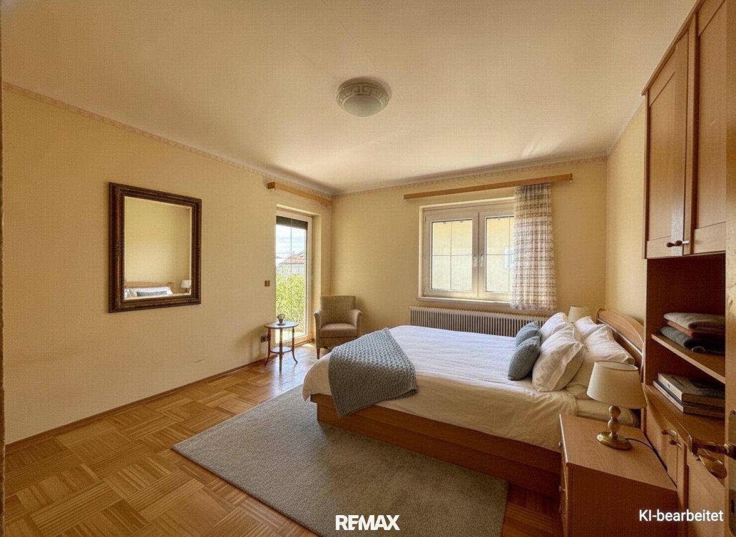 Möbliertes Schlafzimmer mit Doppelbett, Parkettboden und Zugang zum Balkon.