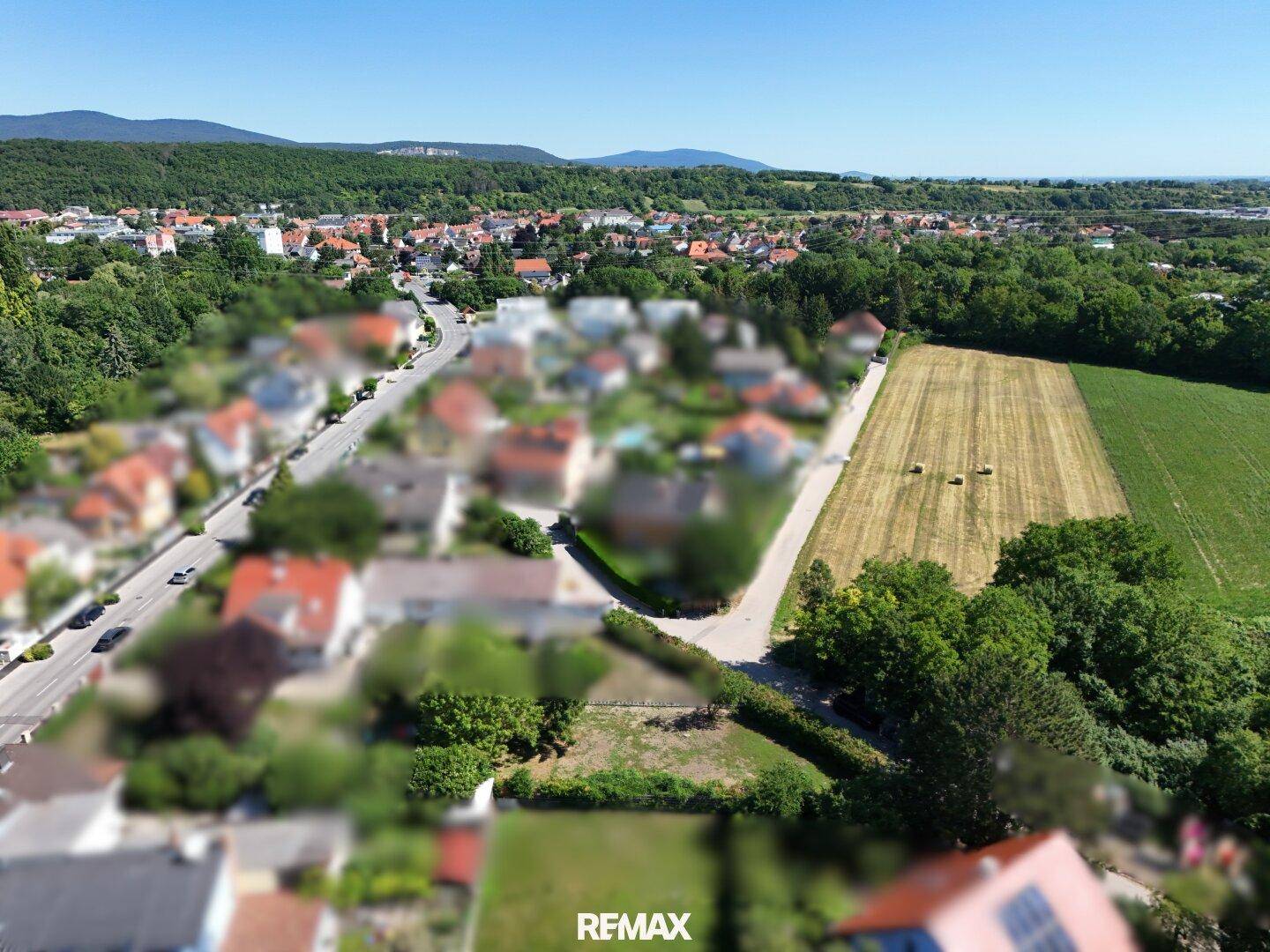Luftaufnahme eines Grundstücks neben einer Straße, umgeben von Wohnbebauung und landwirtschaftlichen Flächen.