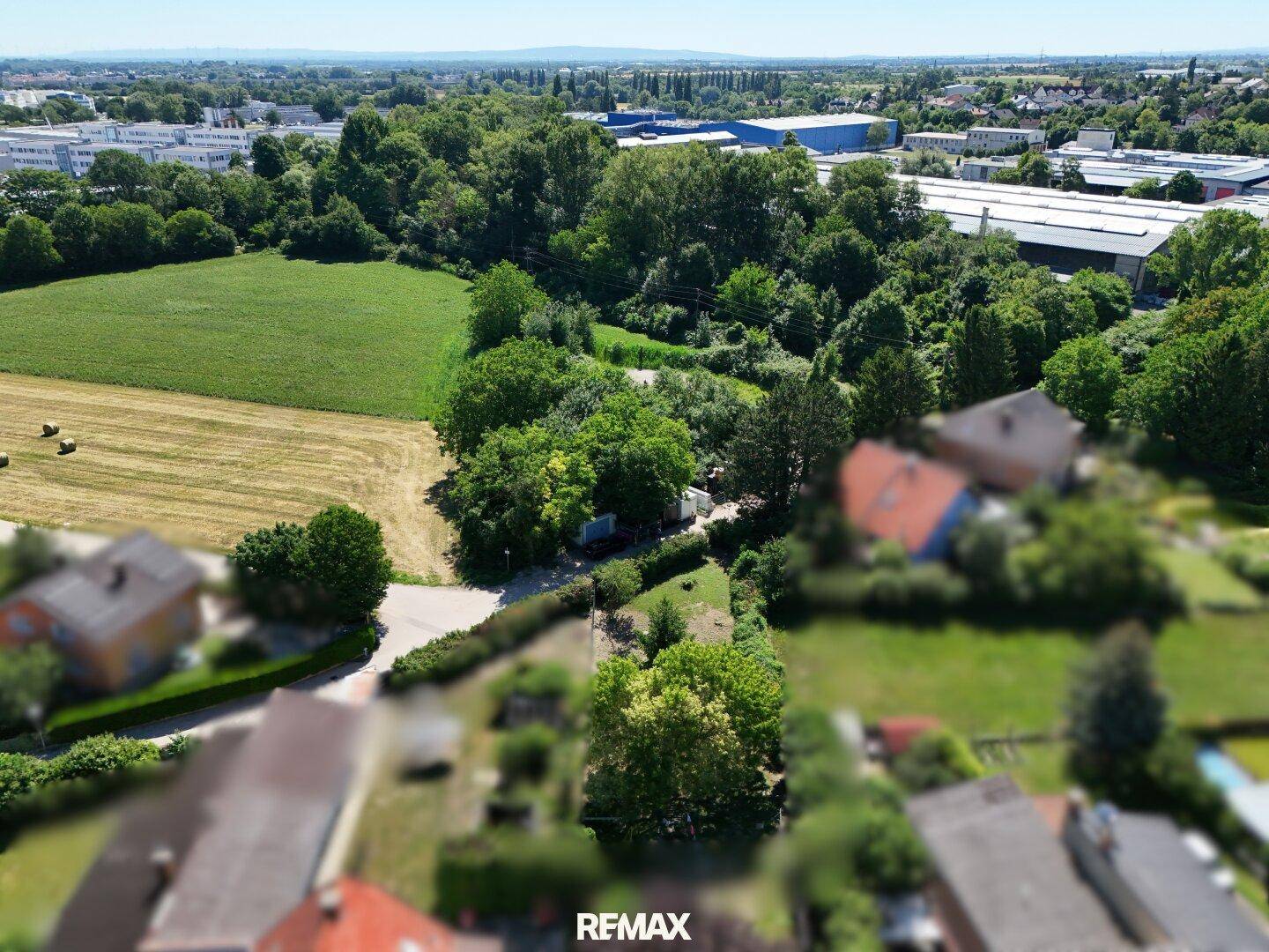 Luftaufnahme eines Grundstücks mit viel Grün, angrenzend an Felder und Gewerbegebiete in der Ferne.