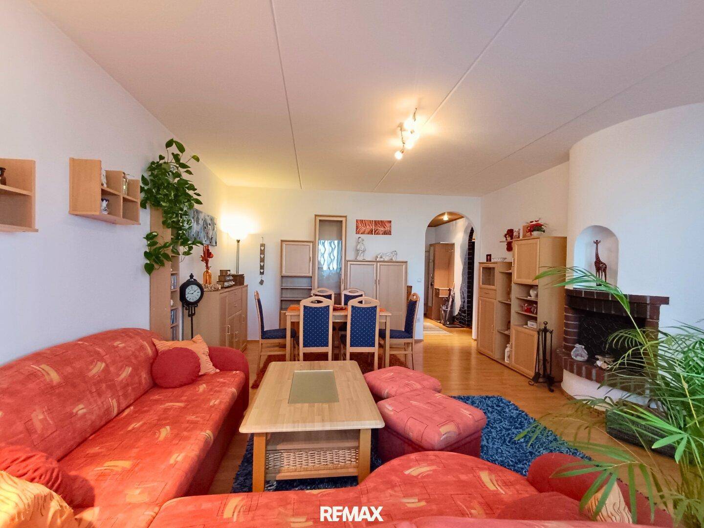 Geräumiger Wohn- und Essbereich mit rotem Sofa, Kamin und traditionellen Holzmöbeln.