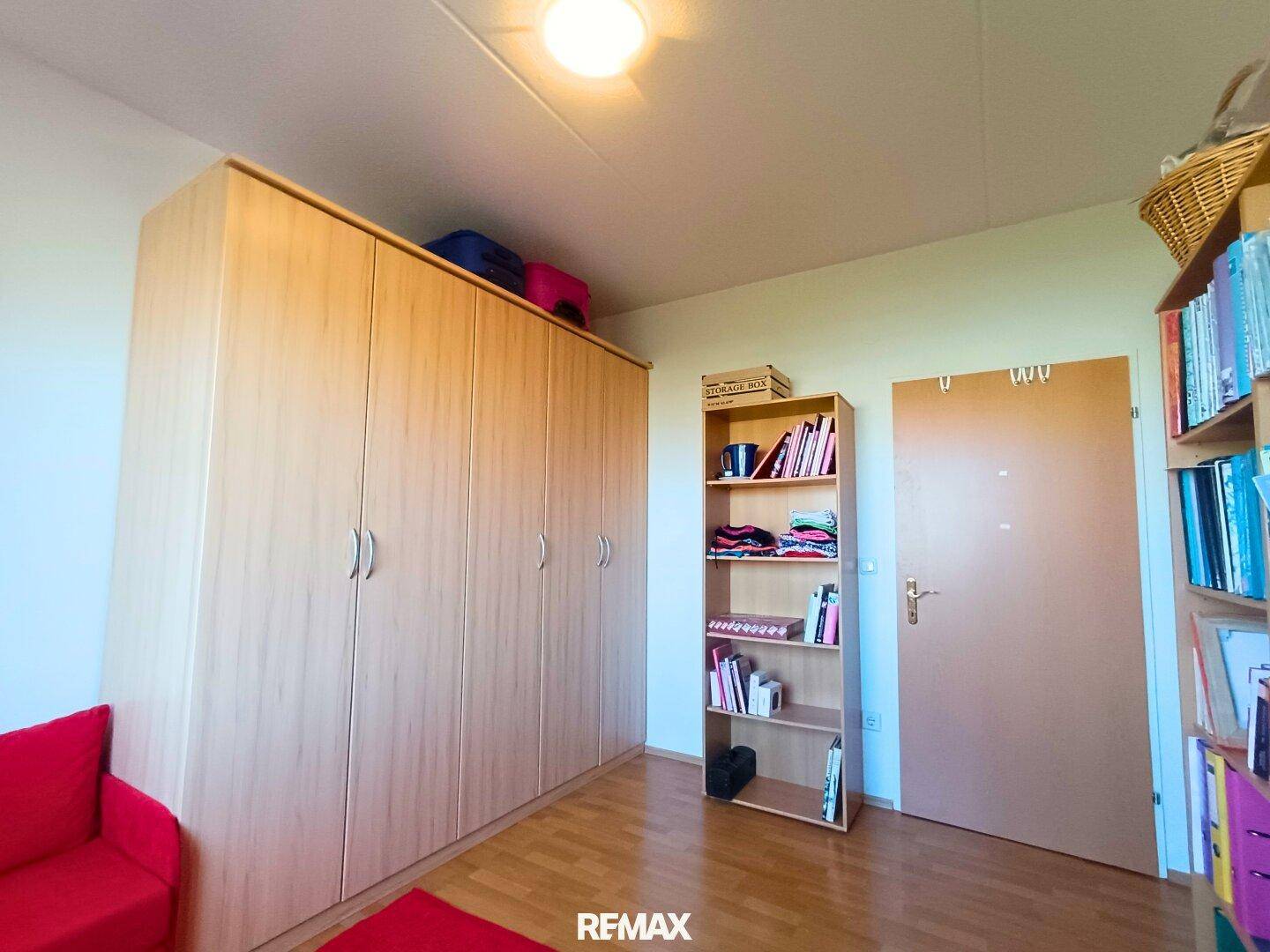 Arbeitszimmer mit großem Kleiderschrank und Bücherregal, bietet viel Stauraum.