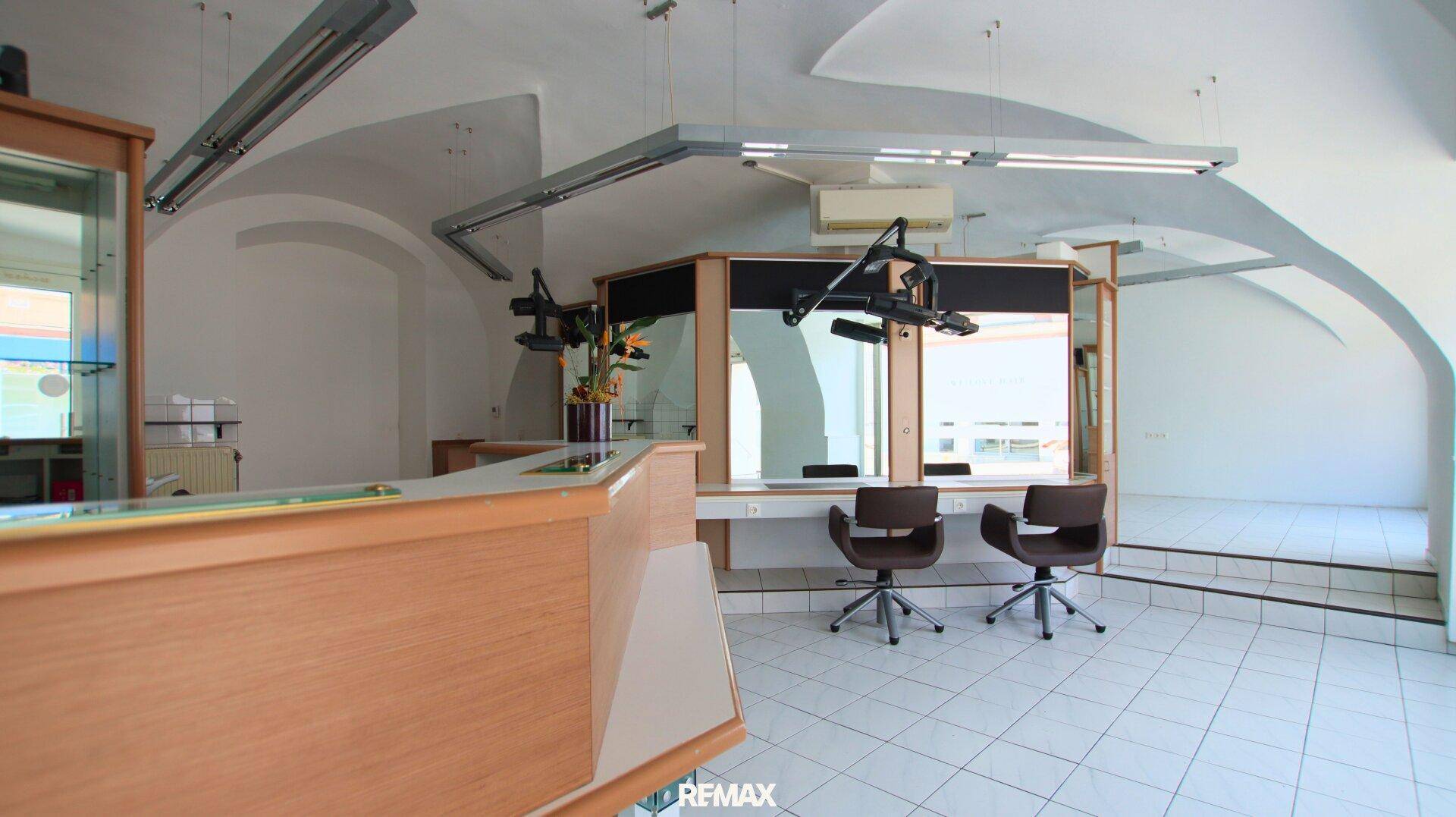 Blick auf den Empfangsbereich eines Friseursalons mit gewölbten Decken und Fliesenboden, der eine helle und offene Atmosphäre schafft.