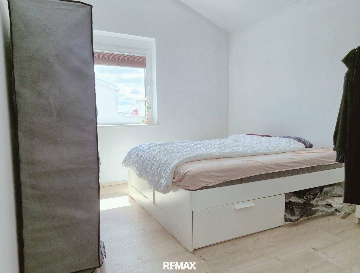Helles Schlafzimmer mit Bett mit Stauraum und einem Fenster.