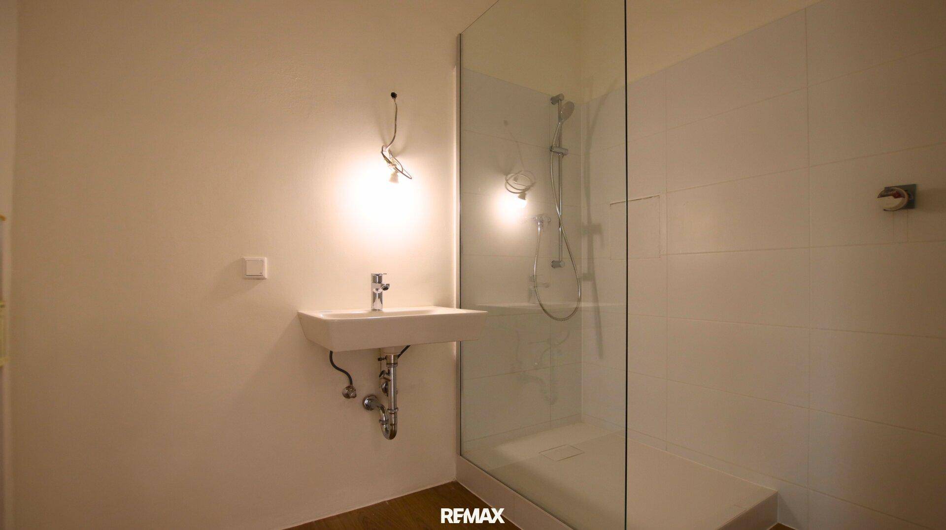 Modernes Badezimmer mit Einzelwaschbecken und geräumiger begehbarer Dusche mit Glaswand.