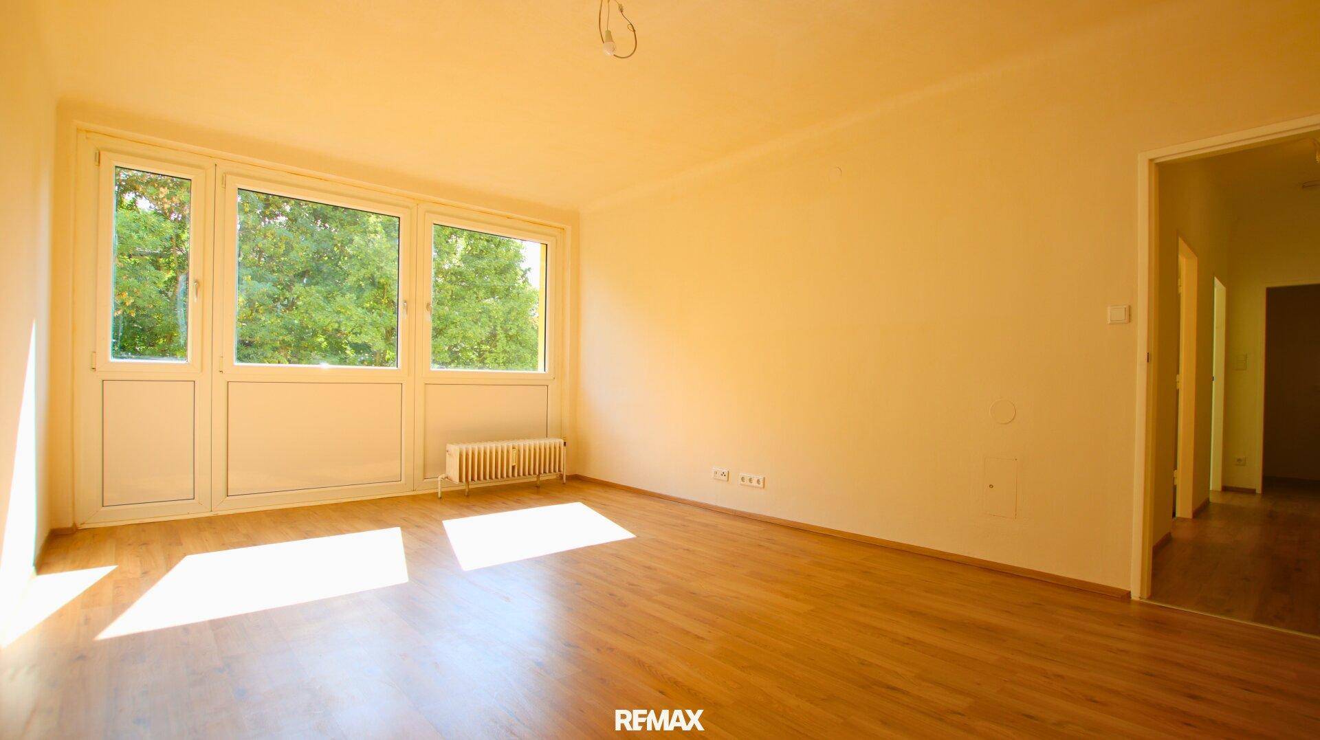 Helles Wohnzimmer mit Holzboden, großen Fenstern und Blick ins Grüne.