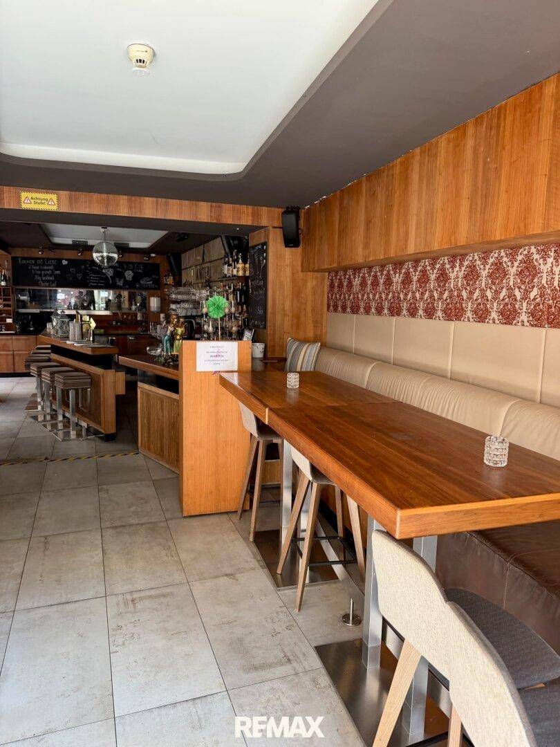 Barbereich mit langer Holztheke und angrenzendem Sitzbereich mit bequemer Bank und Holztisch.