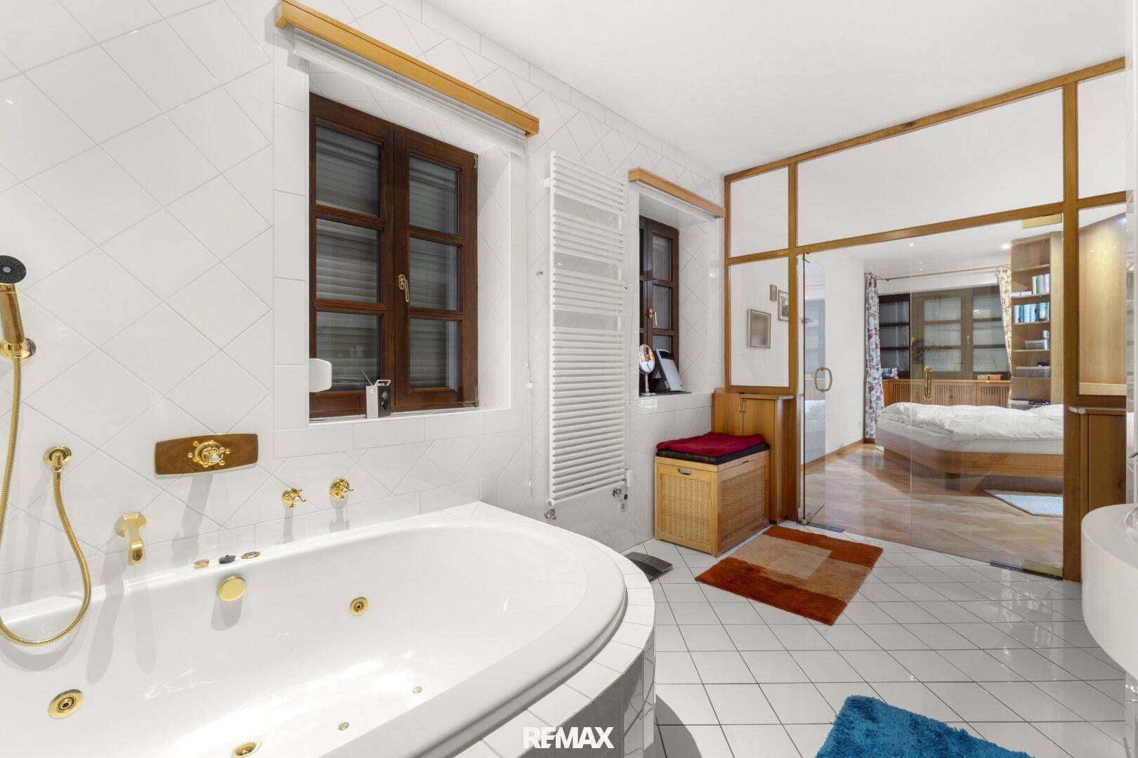 Modernes Badezimmer mit Whirlpool-Badewanne, Fenster und Zugang zum Schlafzimmer.