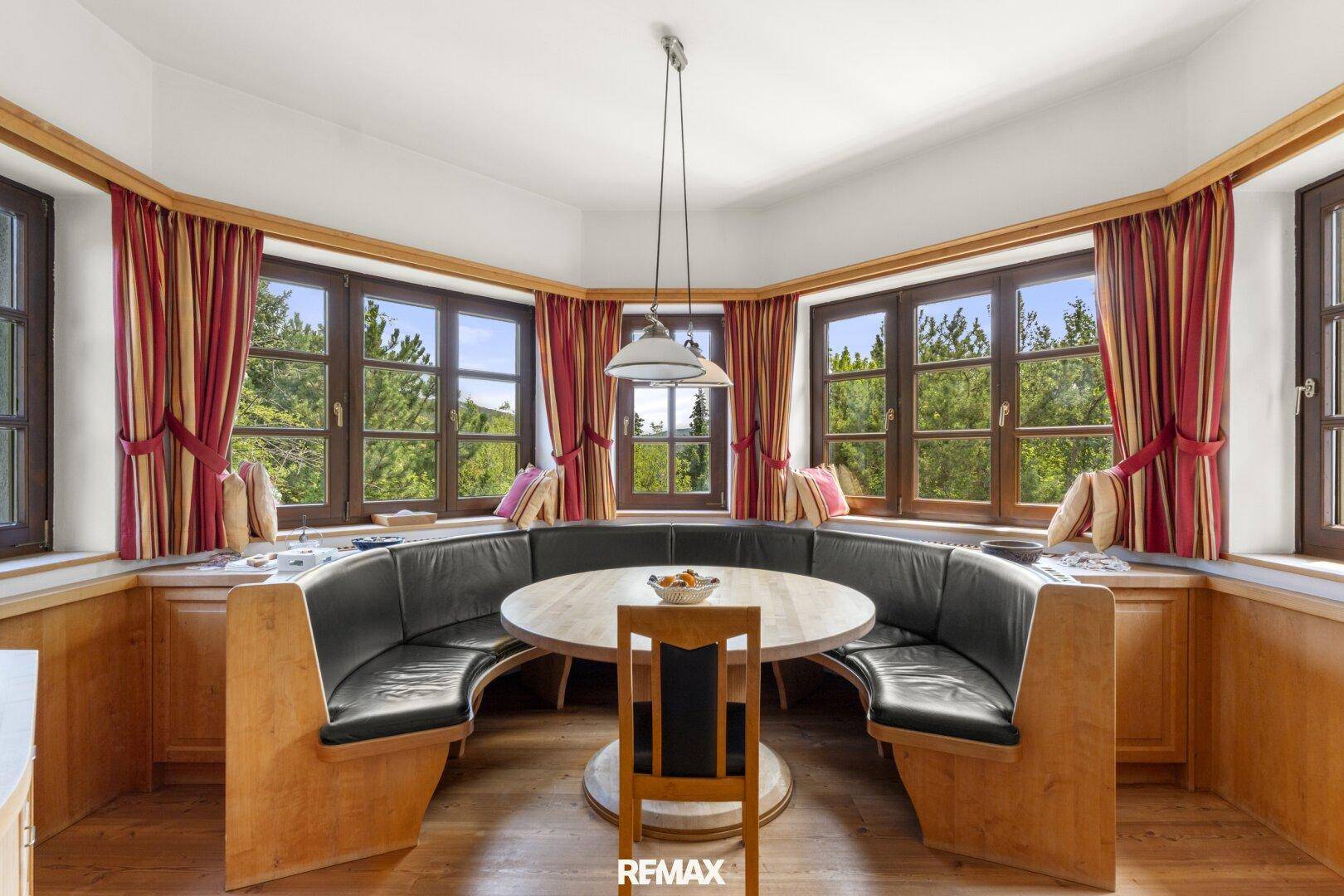 Gemütlicher Essbereich mit Eckbank, Holztisch und Panoramafenstern mit Blick ins Grüne.