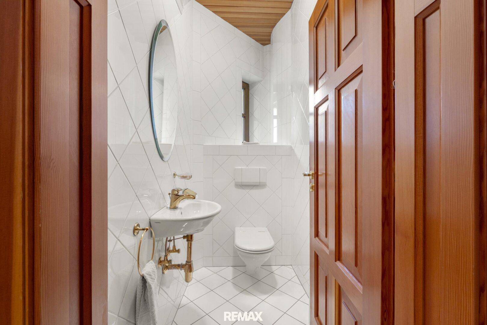 Kleines Gäste-WC mit Fliesenboden, Wand-WC und elegantem Waschbecken.