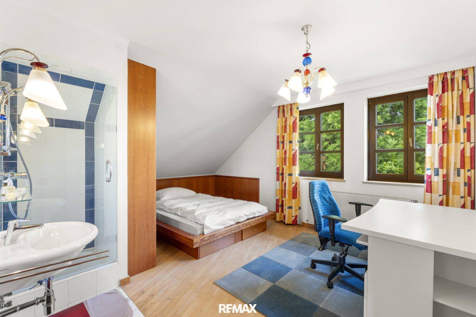 Schlafzimmer mit Holzbett, integrierter Dusche und Blick ins Grüne.
