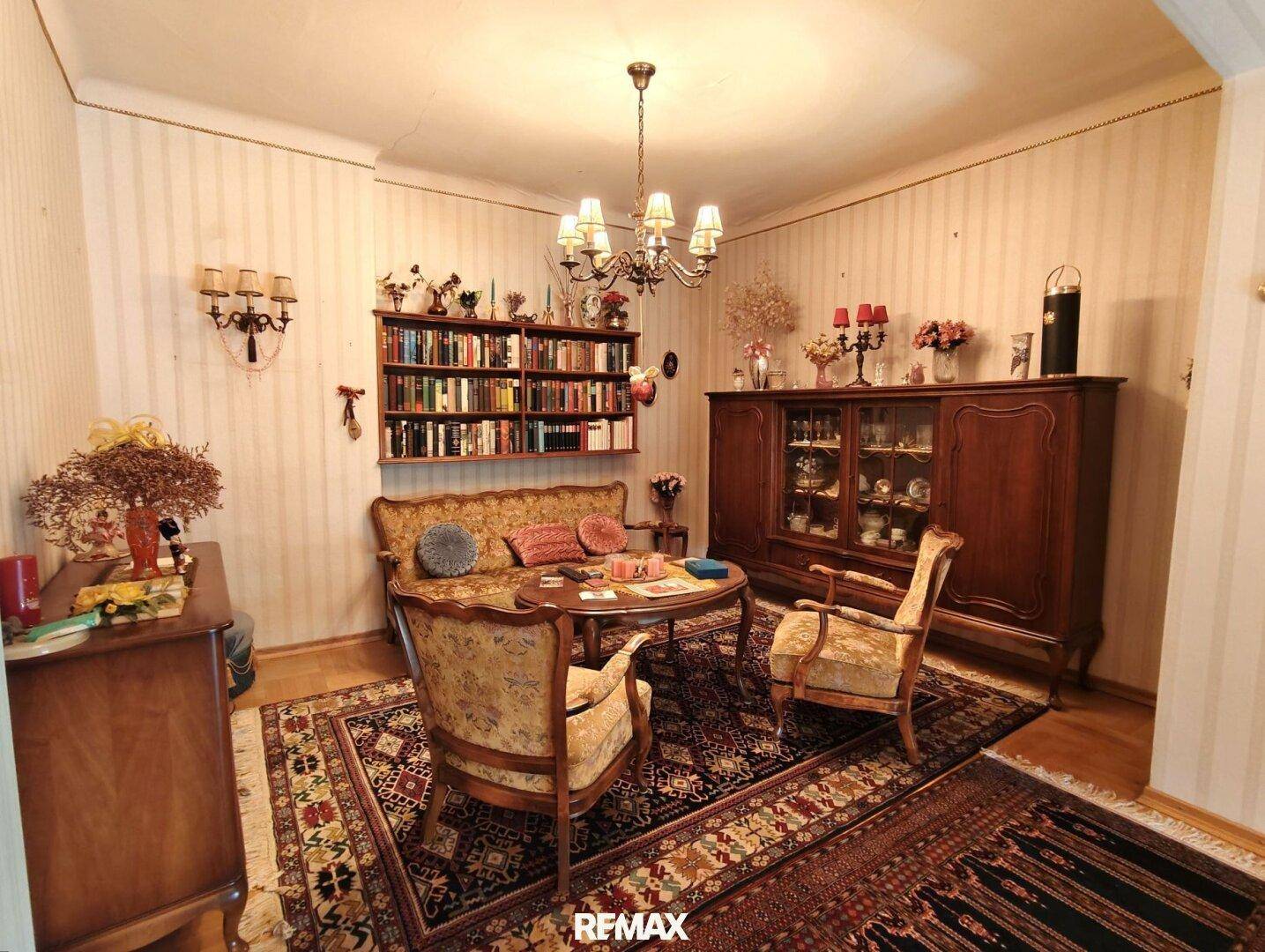 Gemütliches Wohnzimmer im traditionellen Stil mit Teppichboden, Bücherregal und antiken Möbeln.