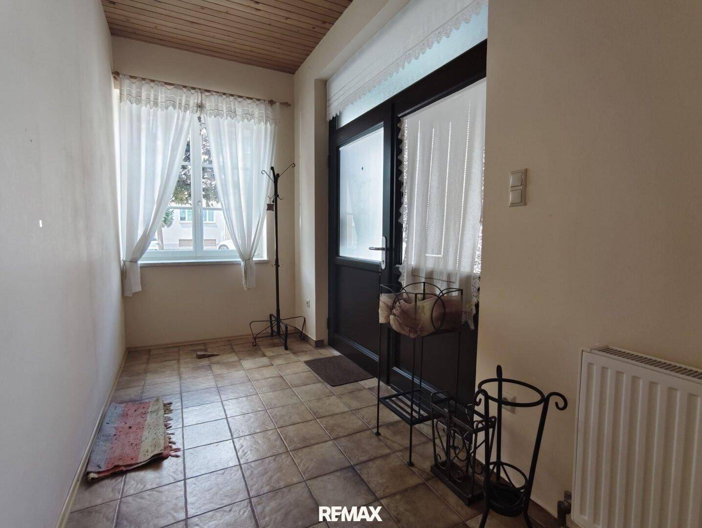 Heller Eingangsbereich mit Fliesenboden, Garderobe und Fenster.