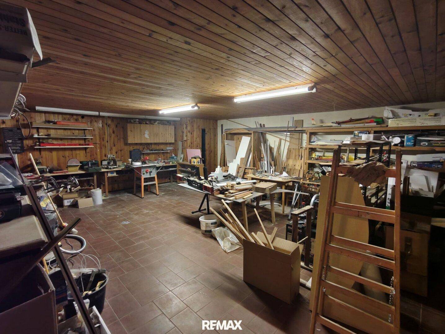 Geräumige Werkstatt mit Holzbalkendecke, Arbeitsflächen und Werkzeugen.