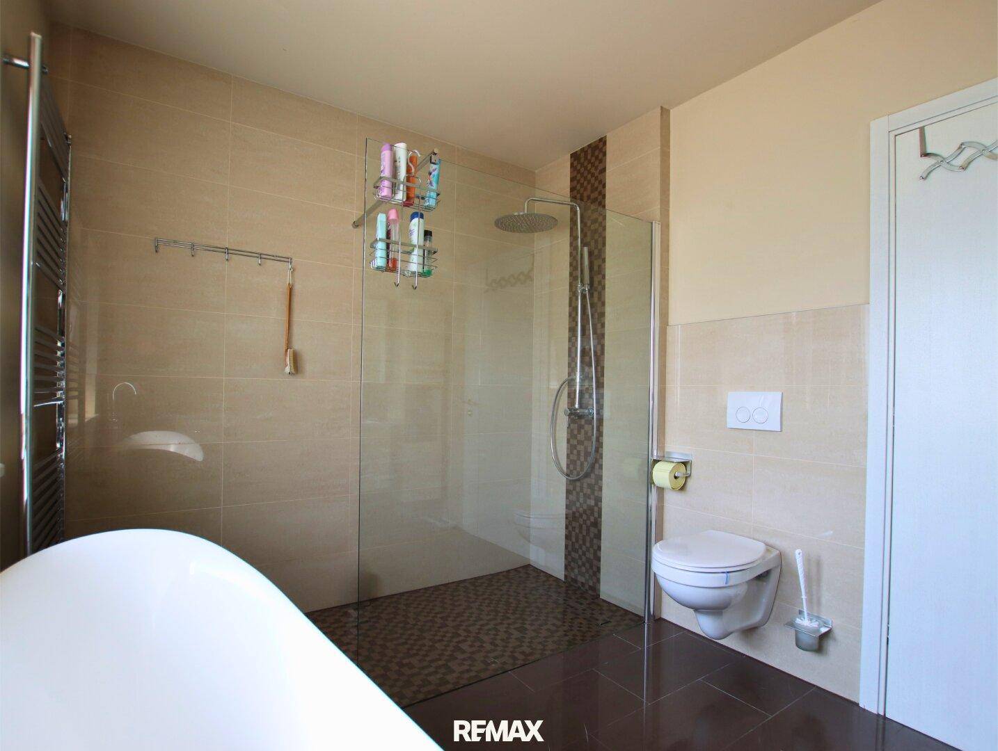 Modernes Badezimmer mit ebenerdiger Dusche, Wand-WC und beigefarbenen Fliesen.
