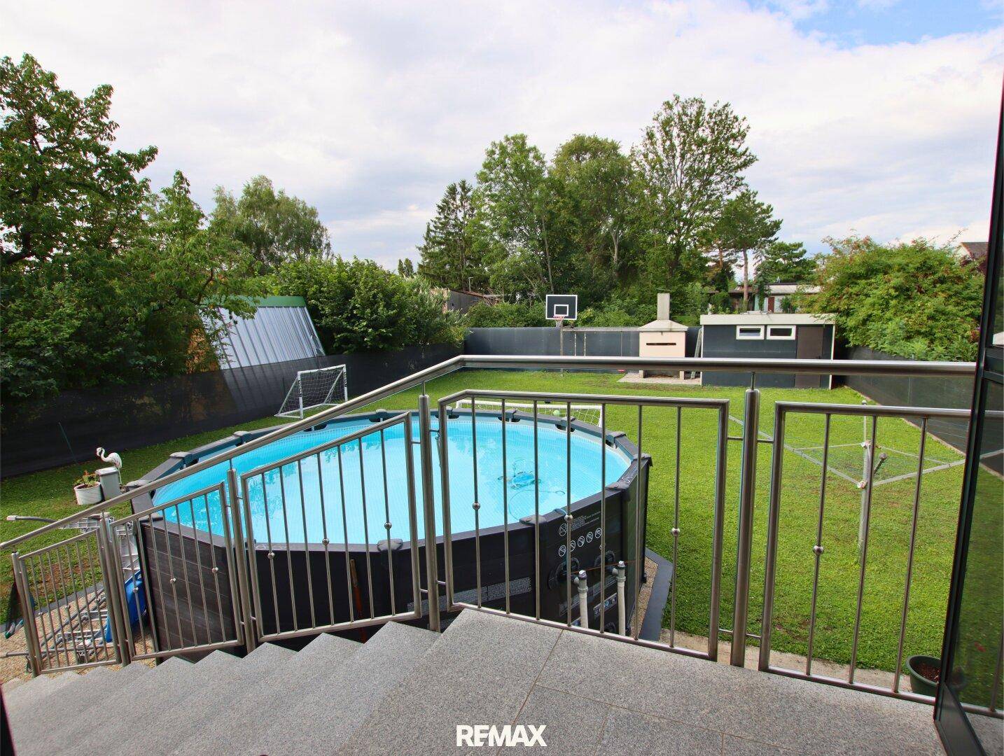 Großer Garten mit Aufstellpool, Grillplatz und Rasenfläche, umgeben von Bäumen.