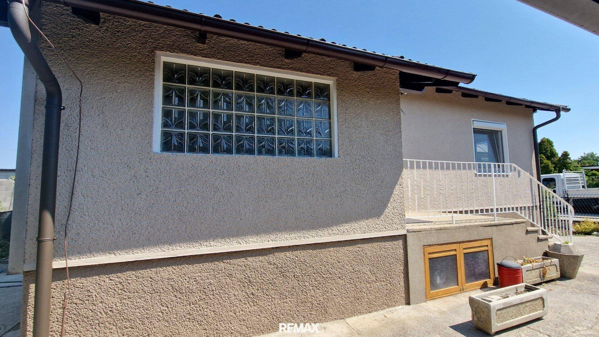 Seitenansicht des Hauses mit Glasbausteinwand und Zugang zum Garten.