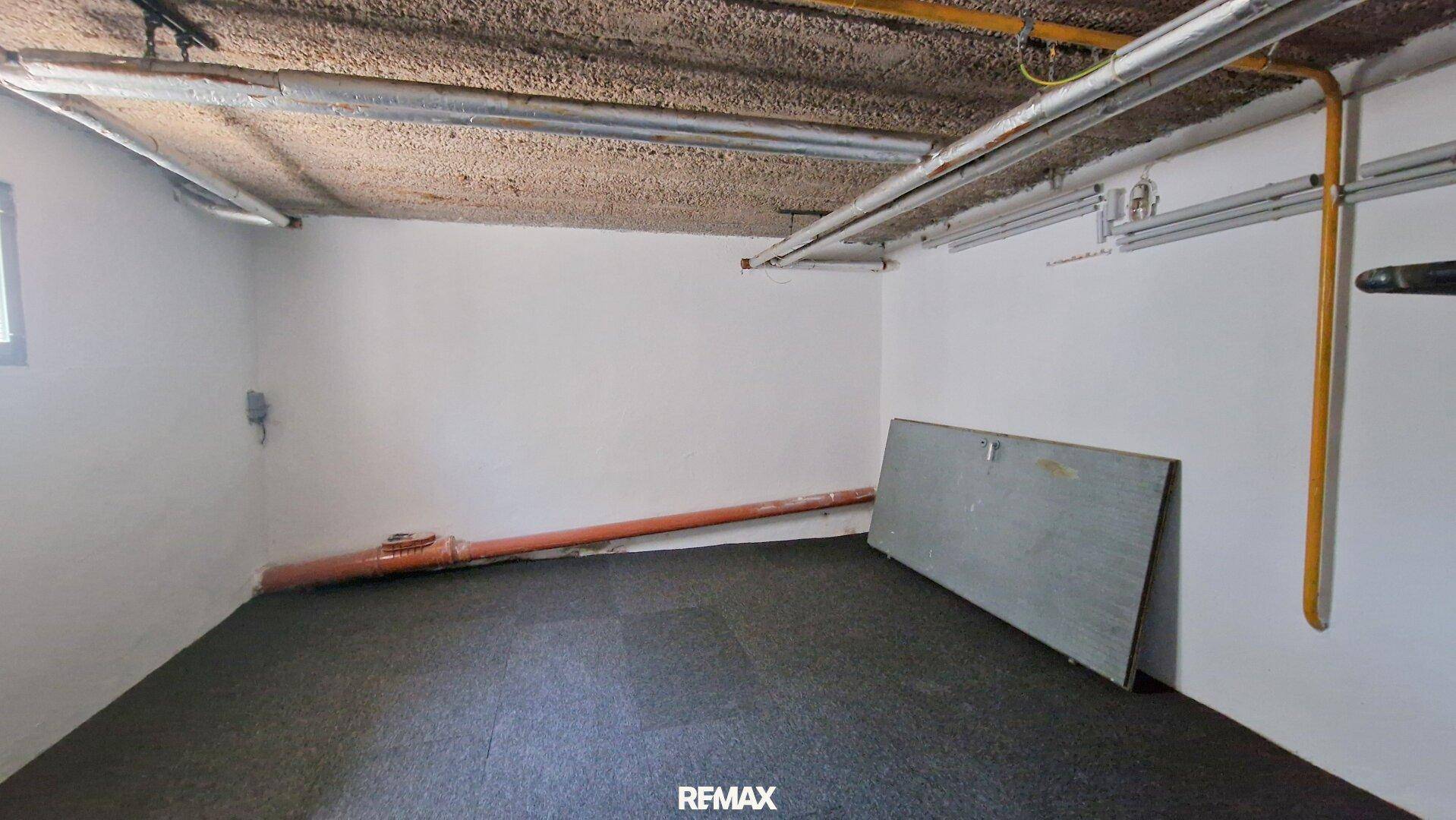 Kellerraum mit dunklem Boden und einer schrägen Platte an der Wand.