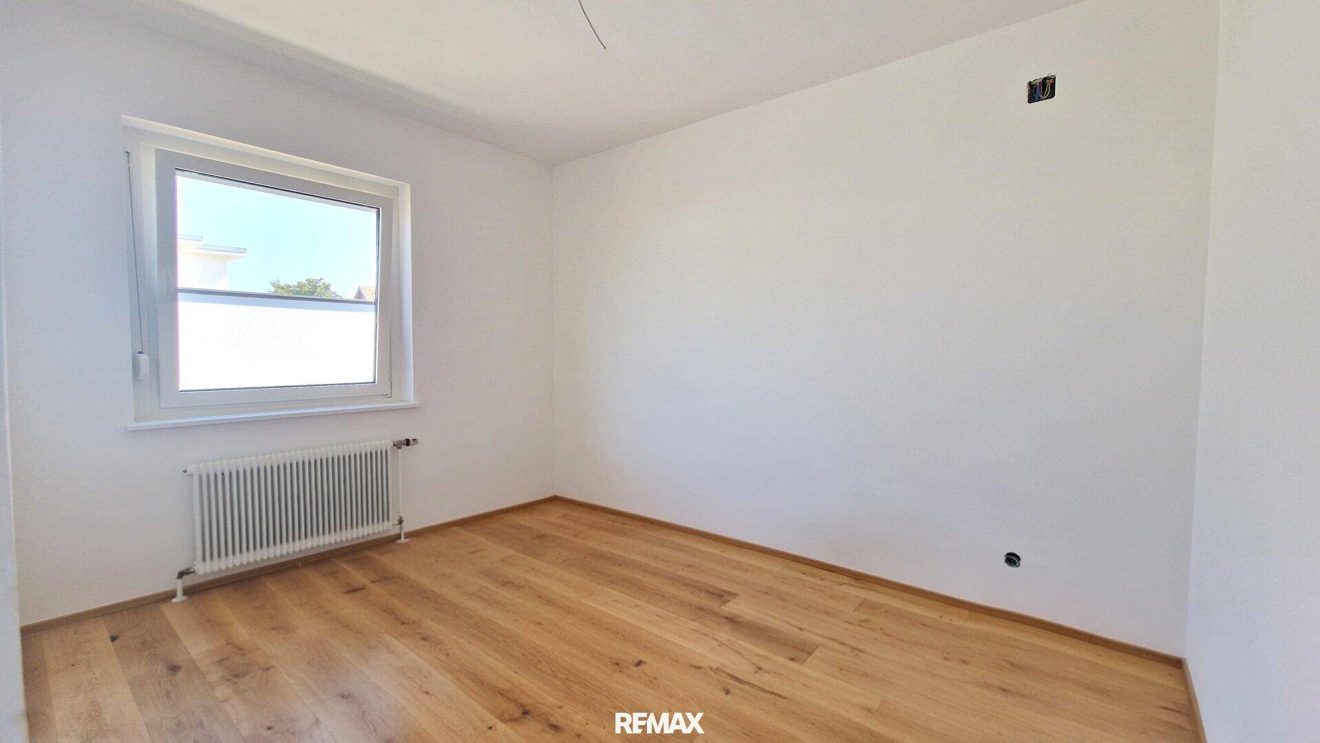 Leeres Schlafzimmer mit Holzboden und einem Fenster, bereit zur Einrichtung.