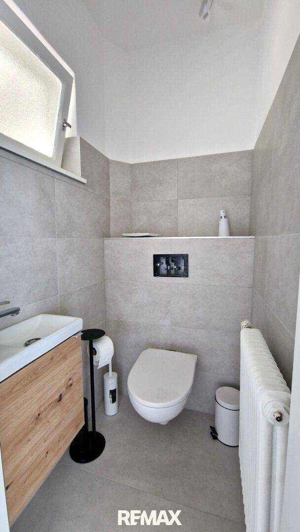 Modernes Gäste-WC mit Wand-WC, Waschbecken und Fenster.