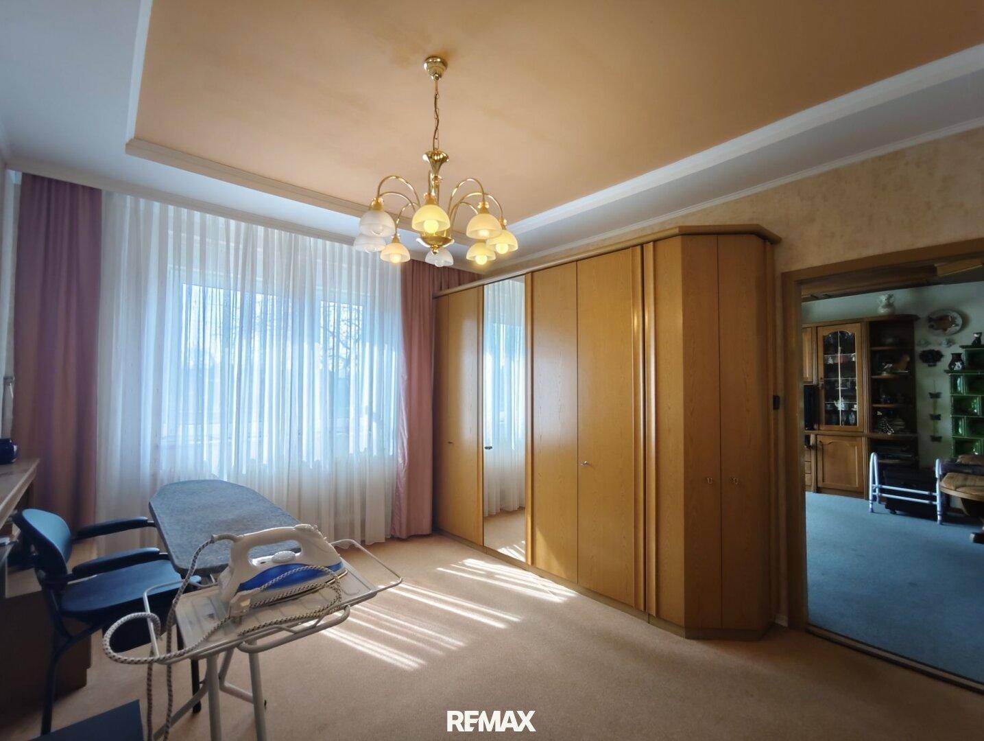 Raum mit großem Spiegelschrank, Teppichboden und einem Fenster, das viel Tageslicht hereinlässt.