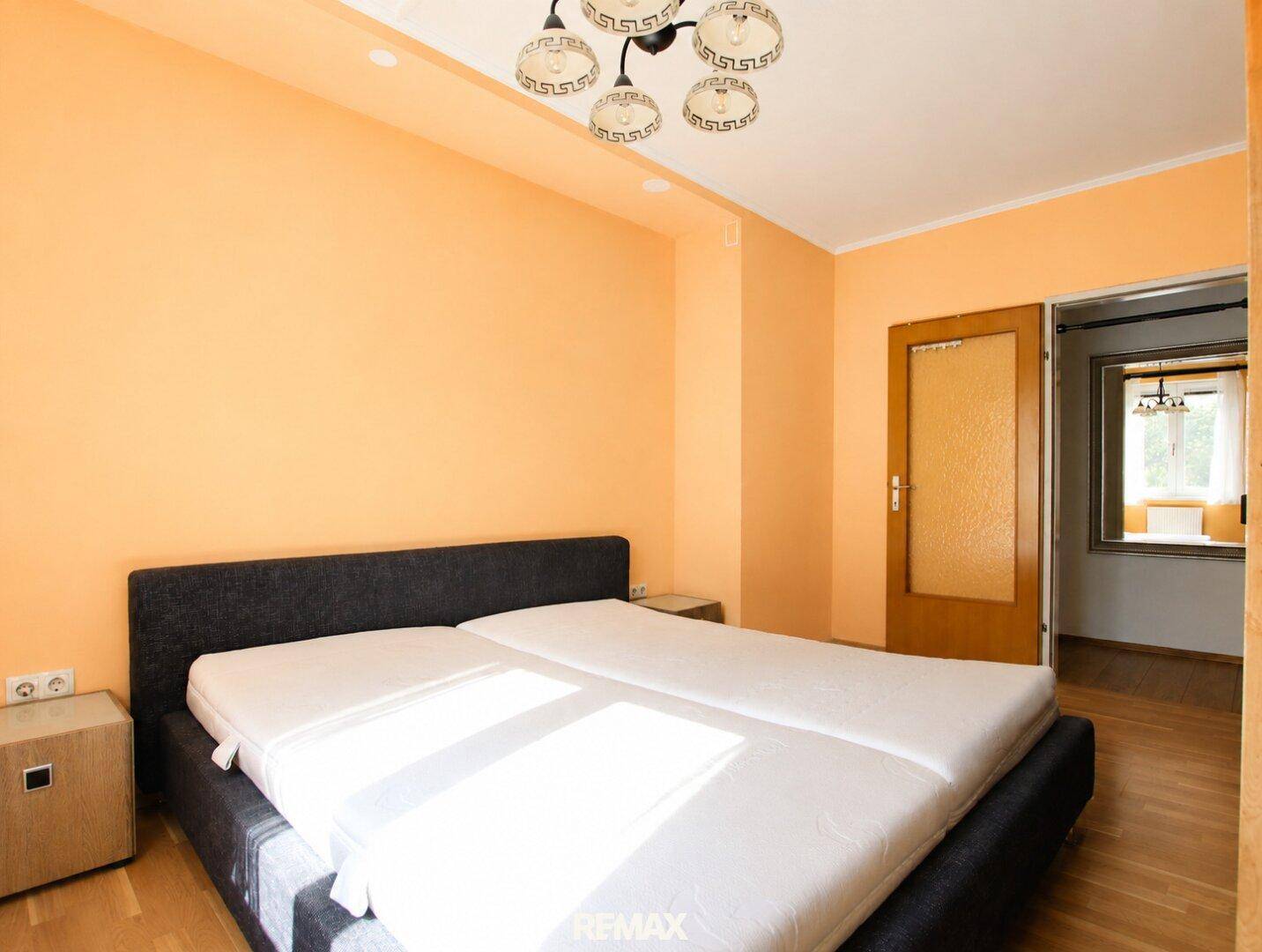 Schlafzimmer mit gelben Wänden und Doppelbett, das zu einem weiteren Raum führt.