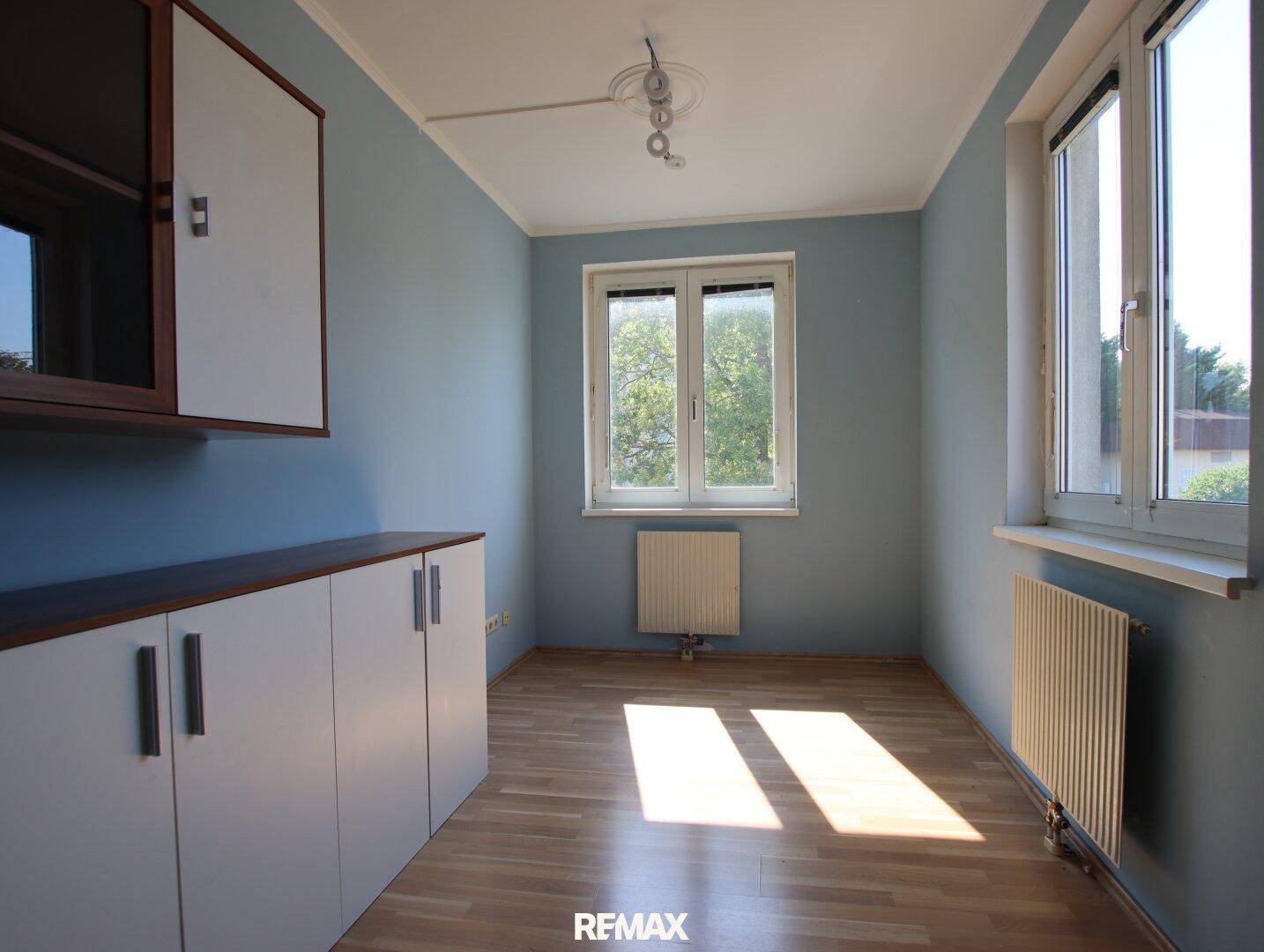 Helles Zimmer mit blauen Wänden, Laminatboden und Einbauschränken.
