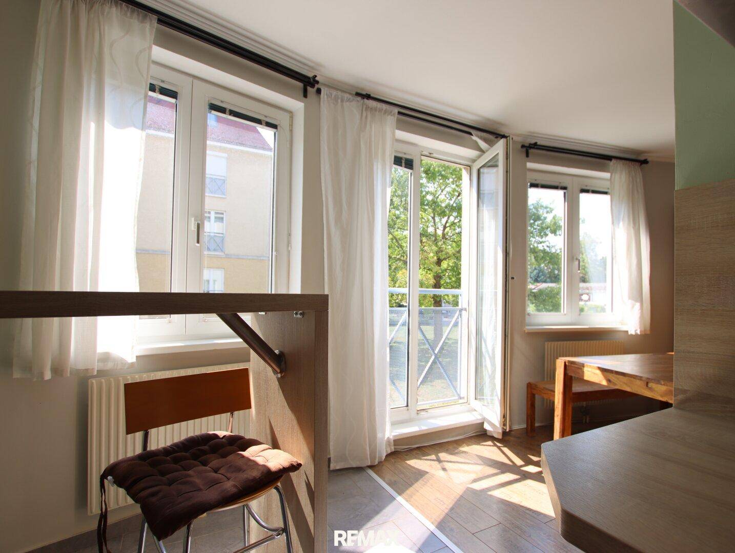 Heller Essbereich mit Zugang zum Balkon und viel Tageslicht durch die Fenster.