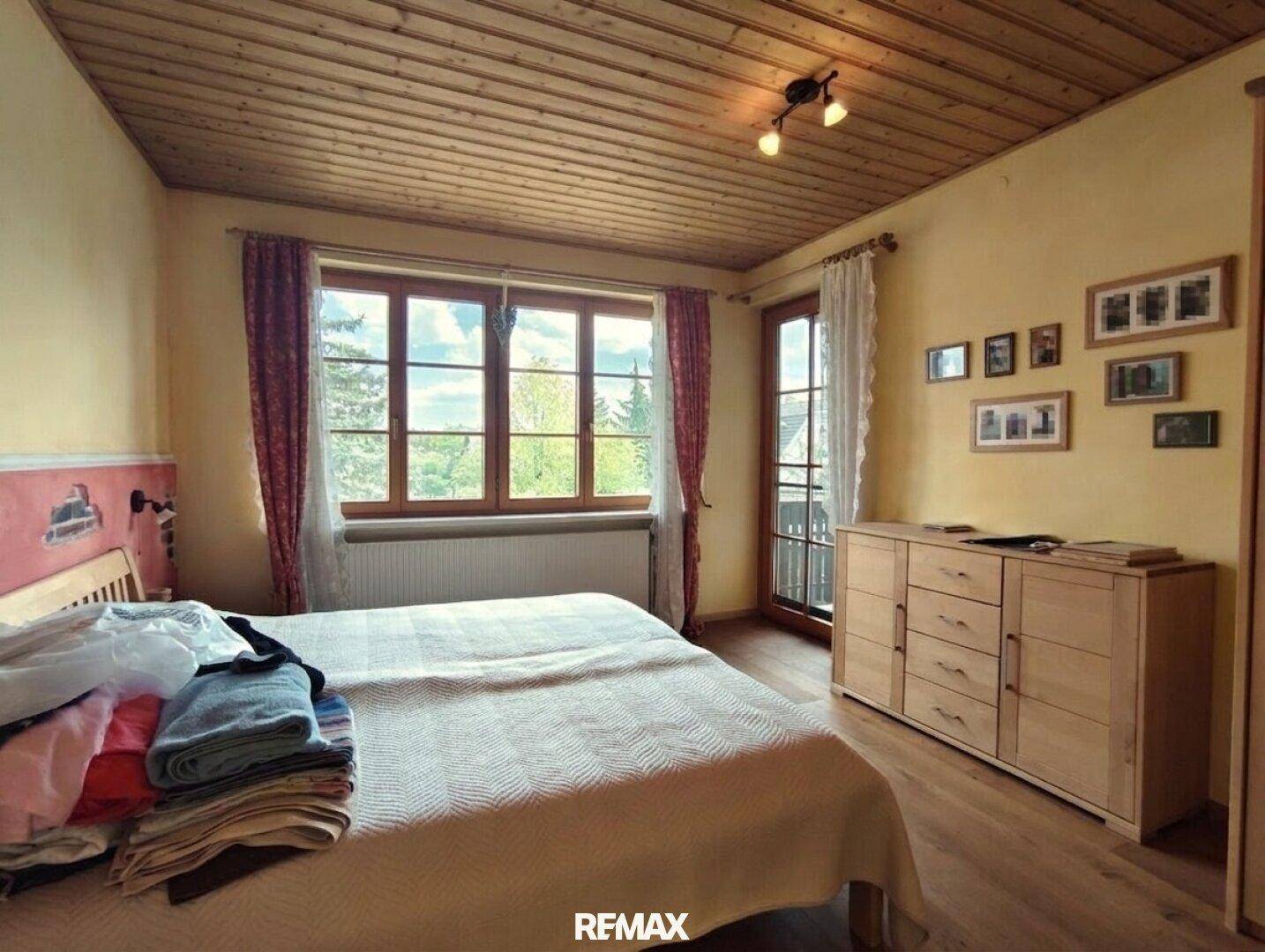 Gemütliches Schlafzimmer mit Holzbalkendecke, Holzboden und Zugang zu einem französischen Balkon.