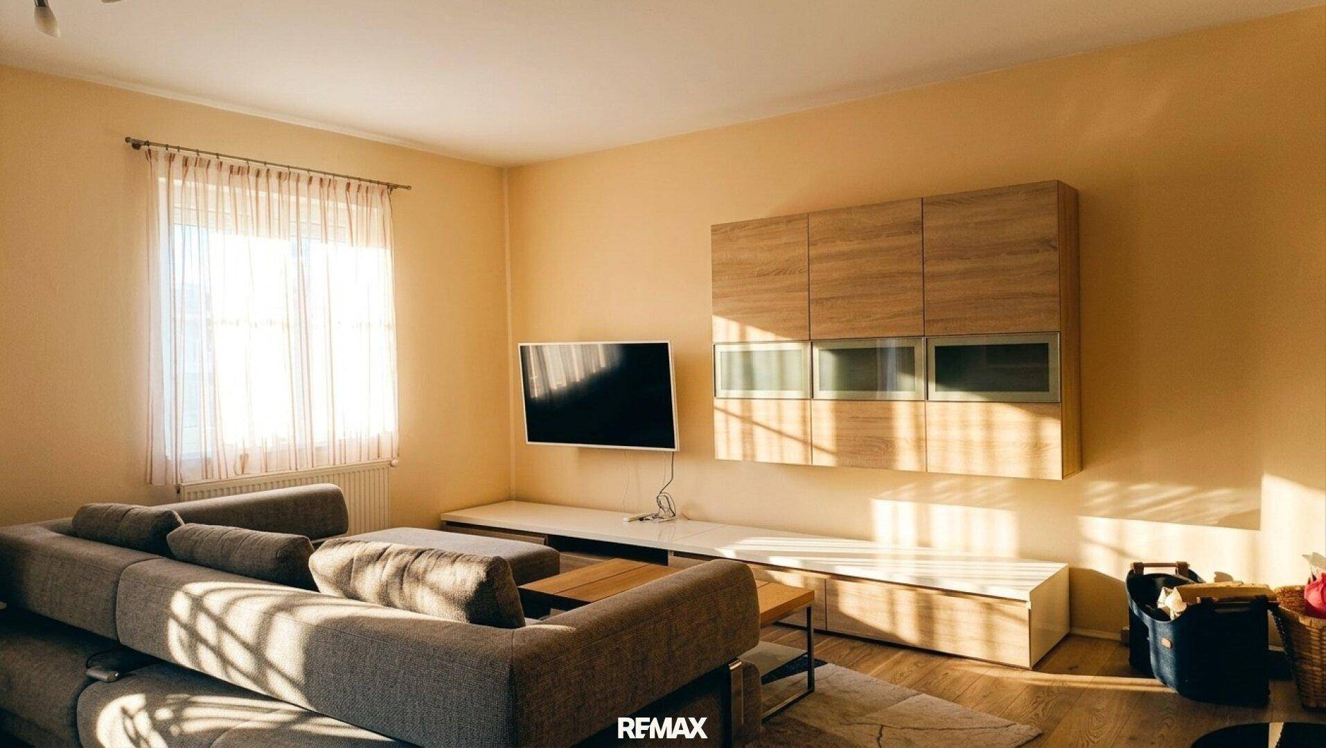 Helles Wohnzimmer mit großem Sofa, modernem TV-Möbel und viel natürlichem Licht.