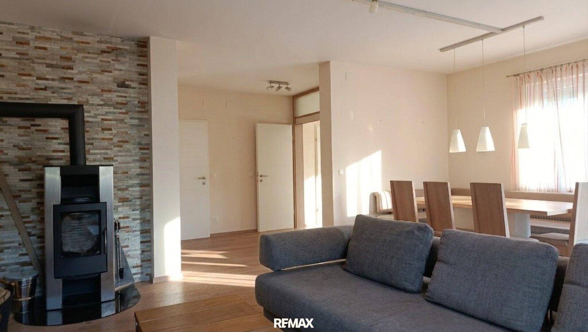 Geräumiges Wohnzimmer mit einem modernen Holzofen und Zugang zu weiteren Räumen.