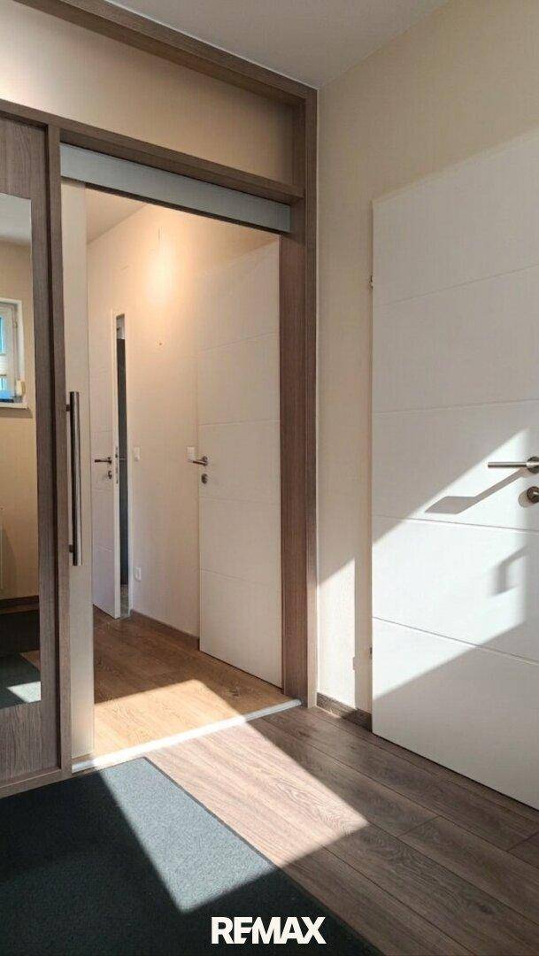 Heller Flur mit Holzfußboden und Zugang zu verschiedenen Zimmern im Haus.