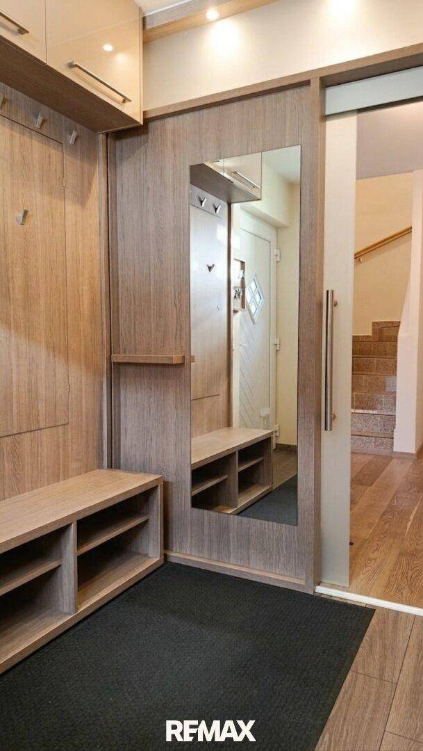 Praktischer Eingangsbereich mit integrierter Holzgarderobe, Spiegel und Schuhablage.