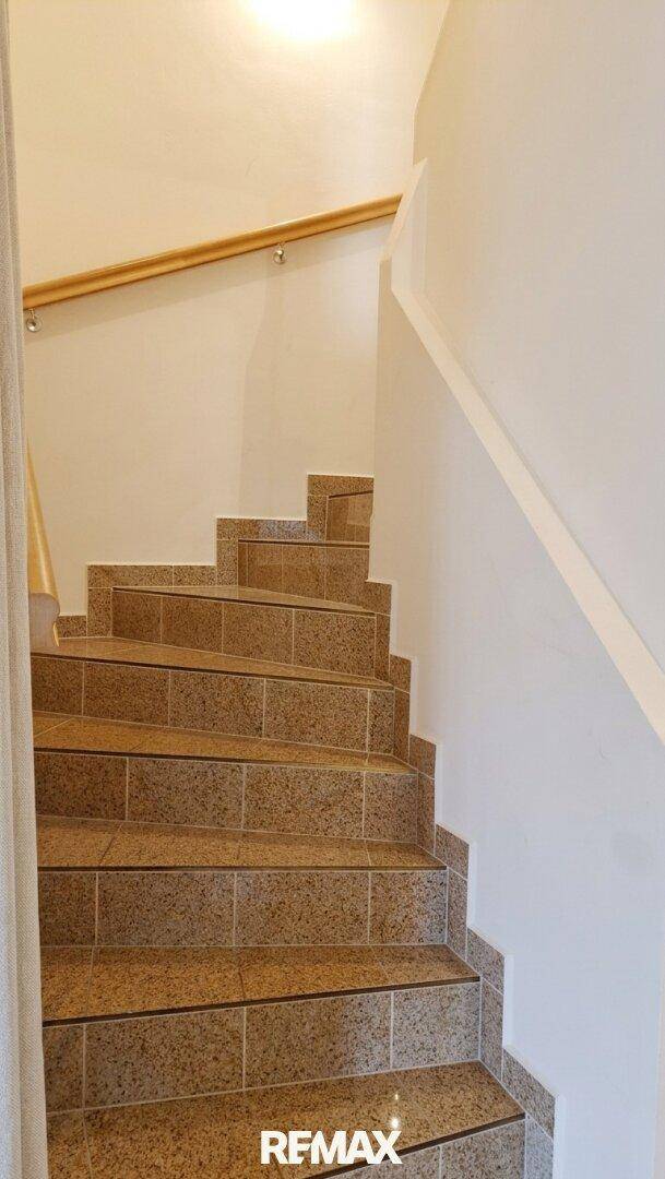 Eine elegante Treppe mit Fliesenstufen und einem stabilen Holzgeländer.