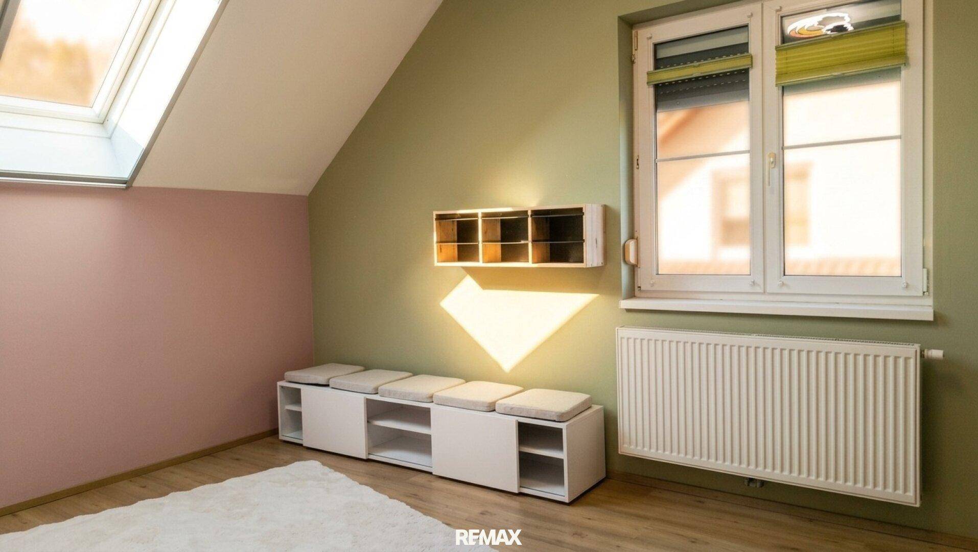Helles Zimmer im Dachgeschoss mit Dachfenster, farbigen Wänden und praktischer Sitzbank.