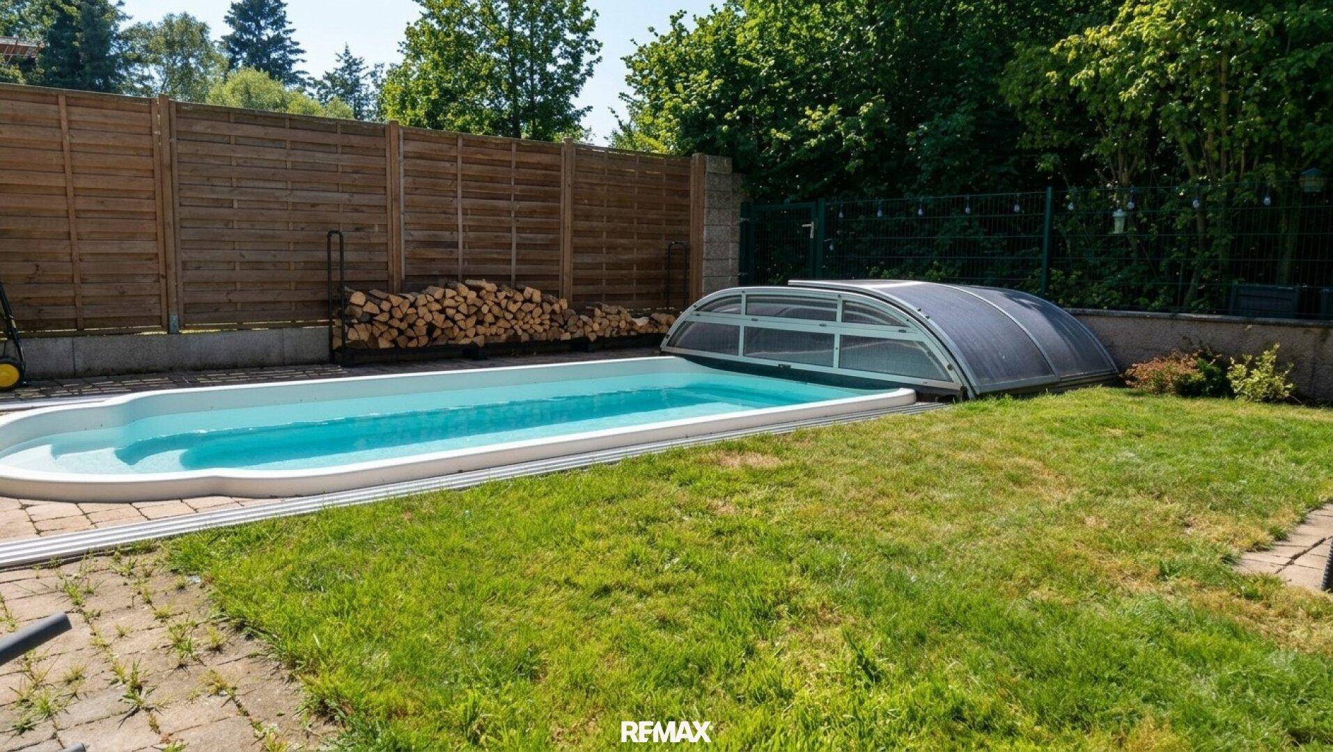 Ein gepflegter Garten mit einem Swimmingpool, umgeben von Rasen und einem Holzzaun.