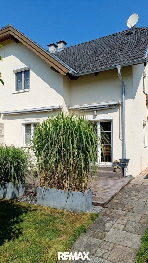 Die Rückseite des Hauses mit einer Holzterrasse und großen Pflanzenkübeln.