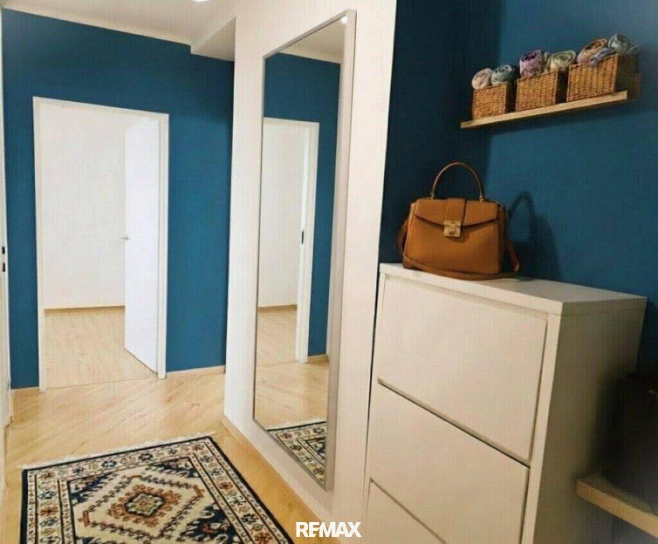 Moderner Flur mit blauen Wänden, großem Spiegel und praktischem Schuhschrank.