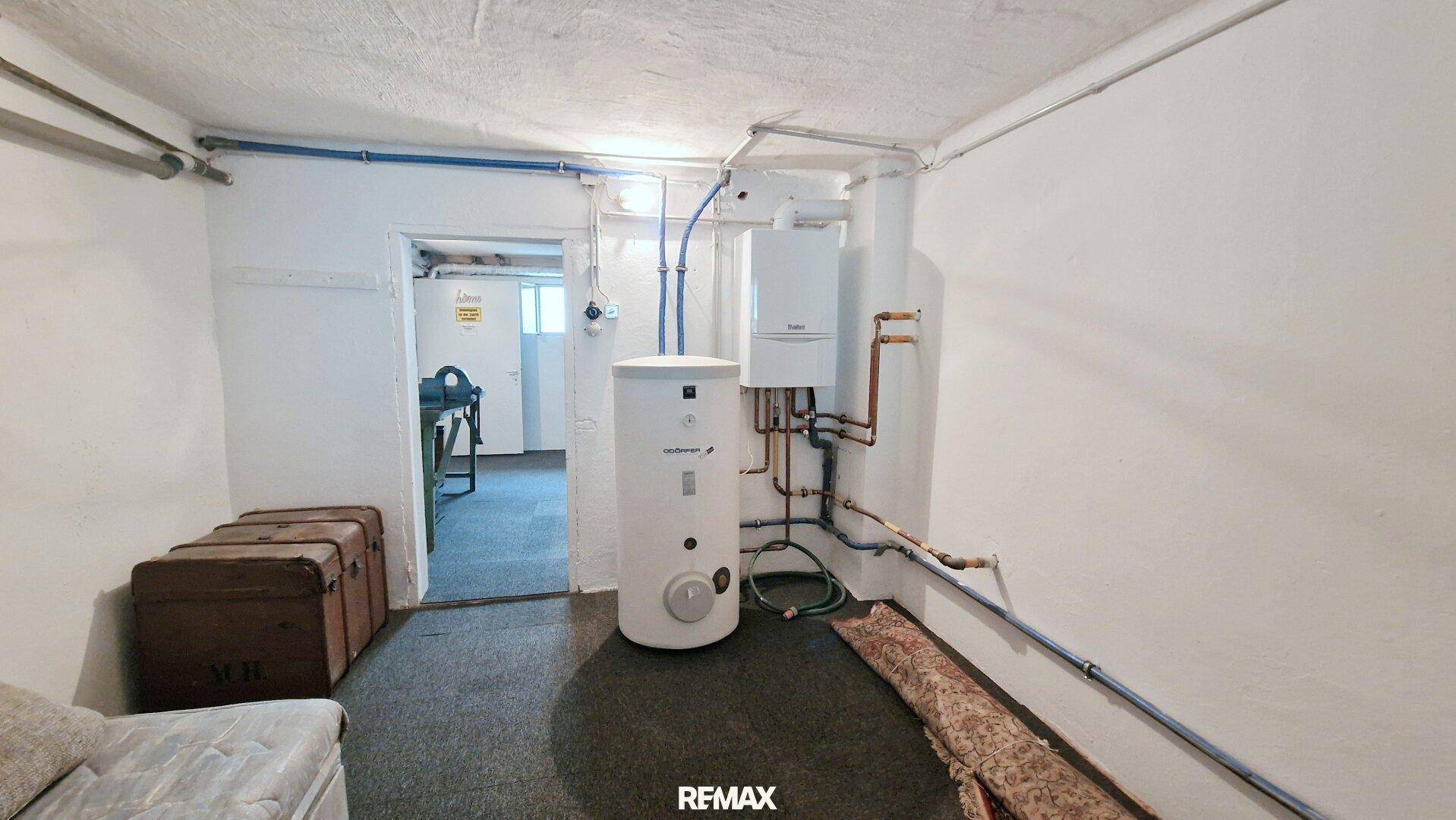 Heizungsraum im Keller mit Warmwasserspeicher, Gastherme und sichtbaren Rohren.