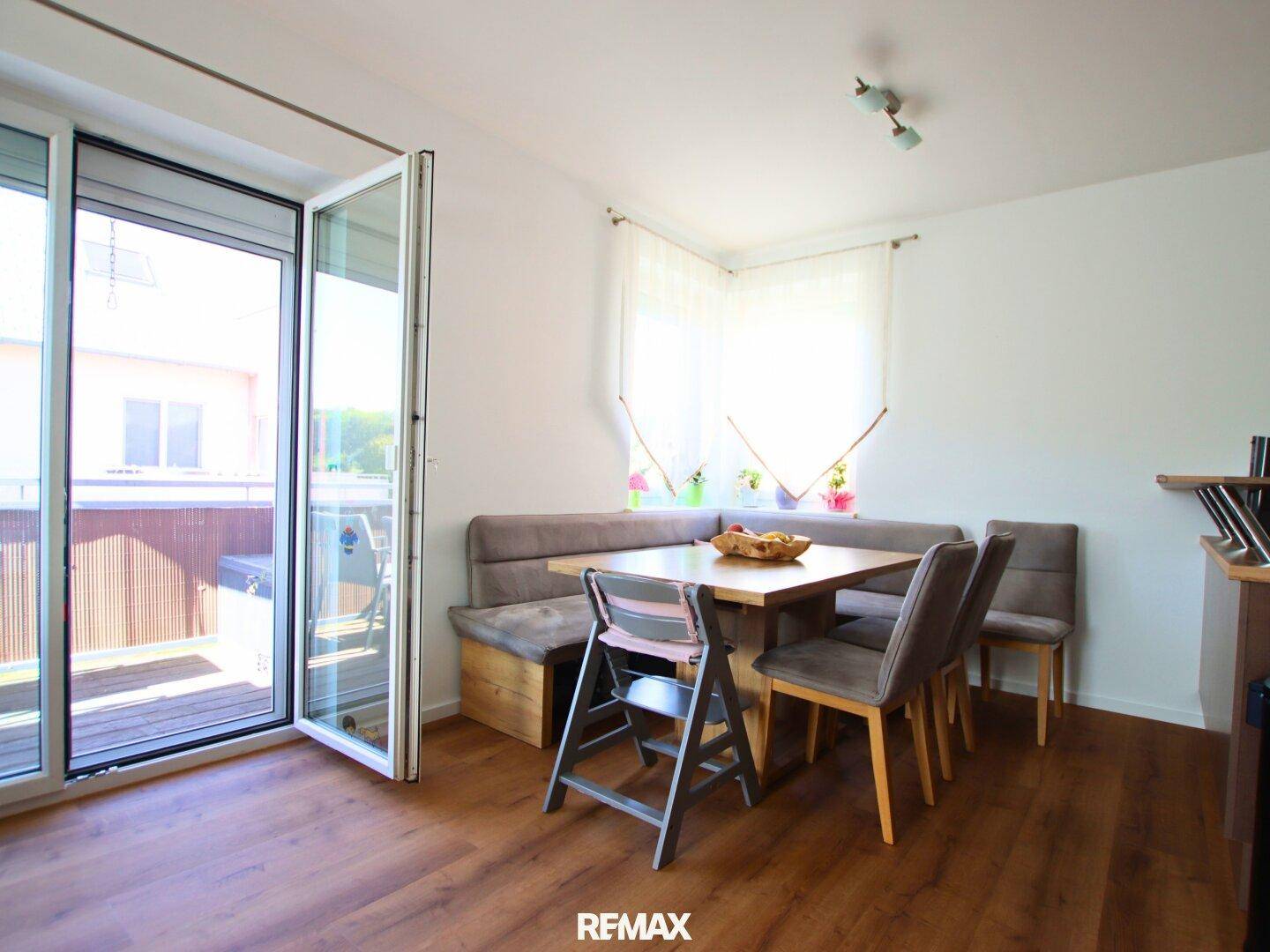 Gemütlicher Essbereich mit Eckbank, Holztisch und direktem Zugang zum sonnigen Balkon.