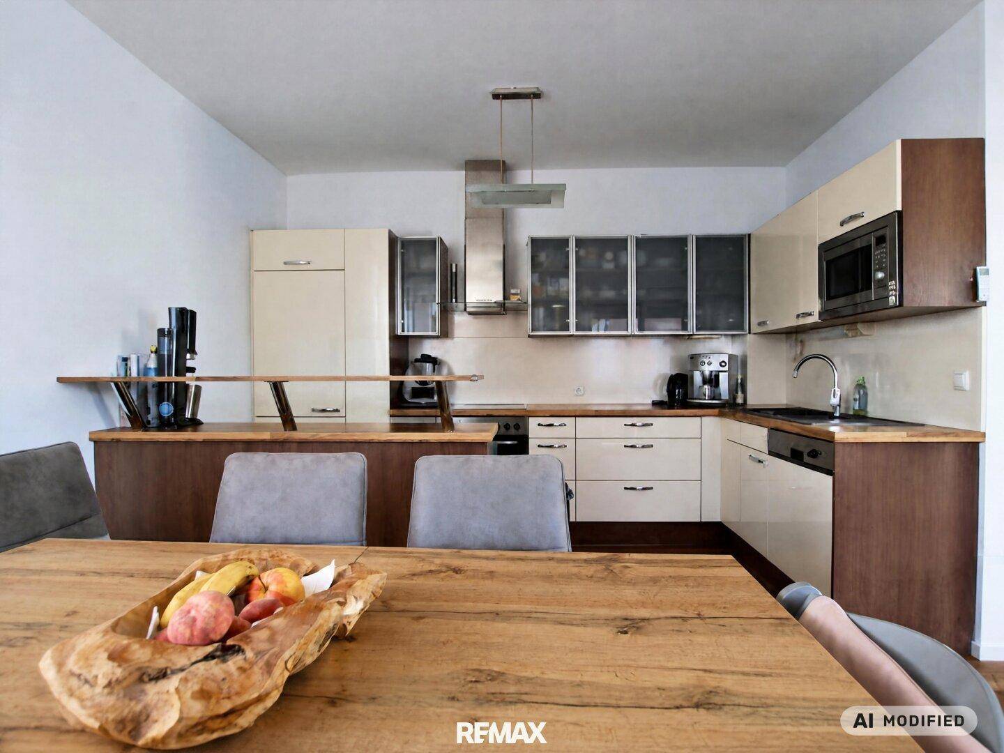 Moderne Einbauküche mit Holztheke, integrierten Geräten und Essbereich im Vordergrund.