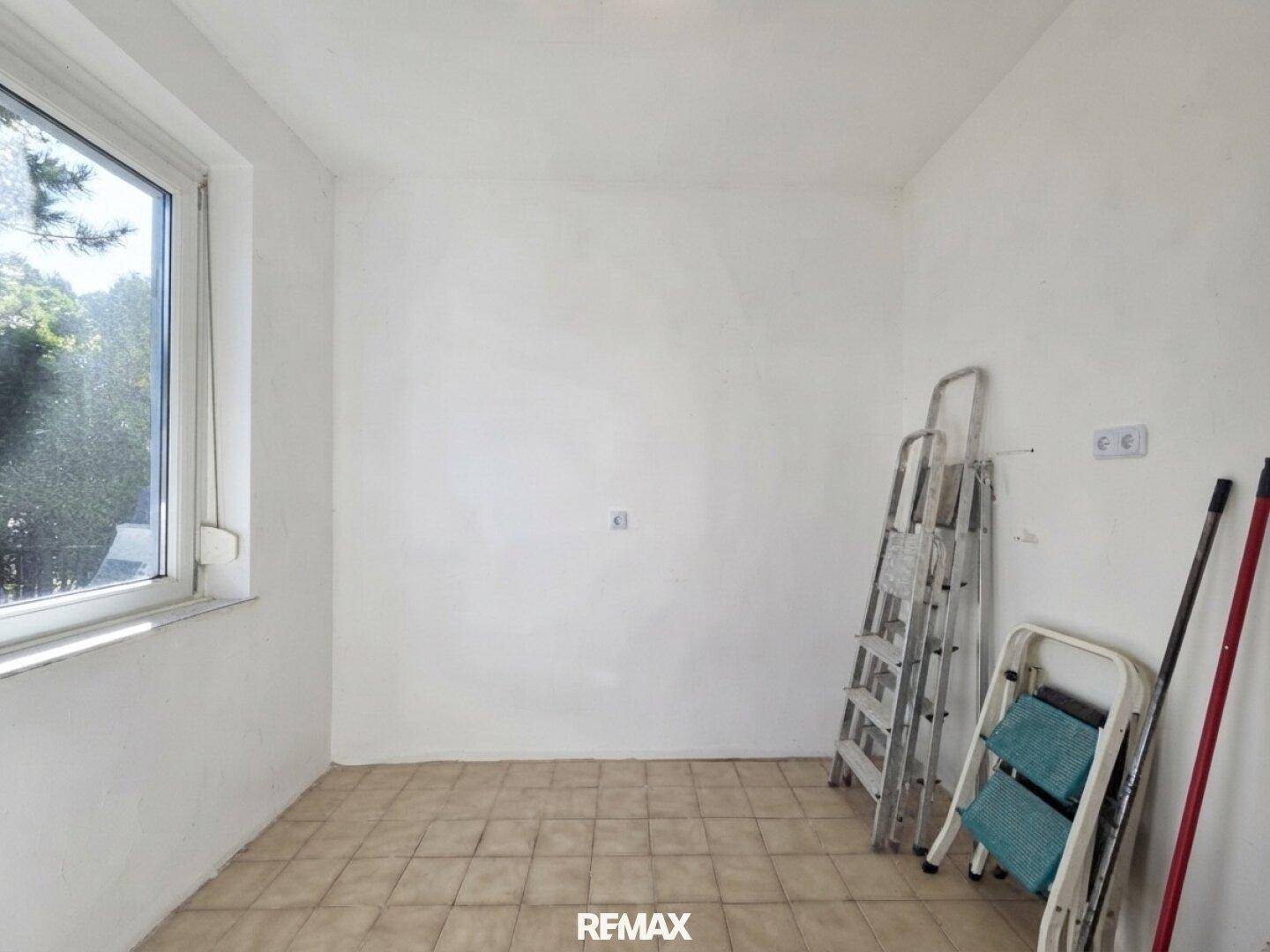 Leerer Abstellraum mit Fenster, Fliesenboden und einfacher Ausstattung.