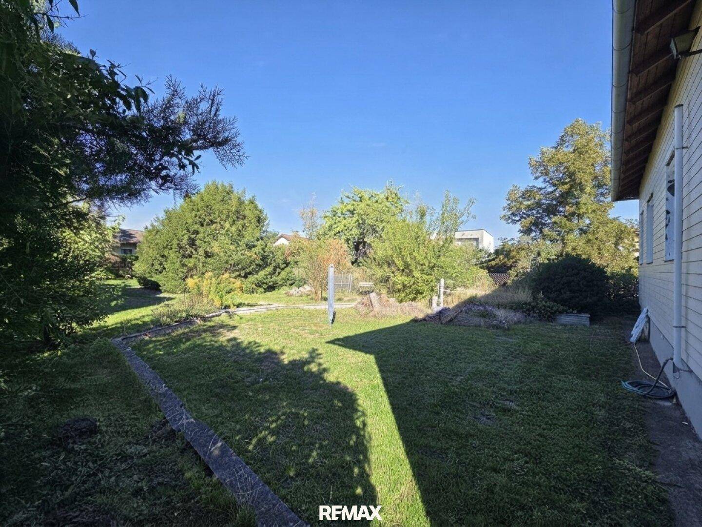Großer Gartenbereich mit Rasenfläche und altem Baumbestand neben dem Haus.