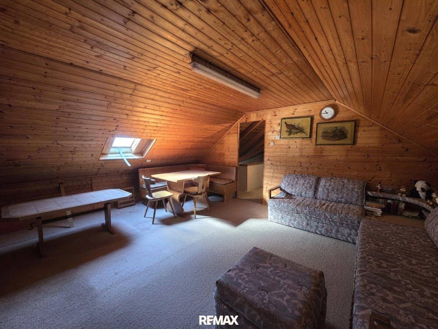 Gemütlich ausgebauter Dachboden mit Holzverkleidung, Dachfenster und Wohnbereich.