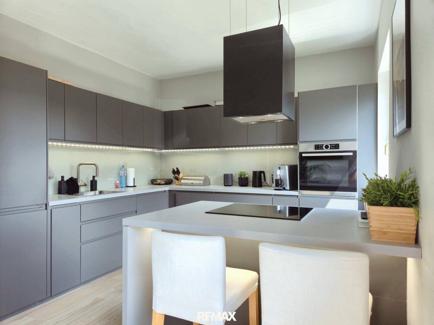 Moderne Küche mit grauen Hochglanzfronten, Kücheninsel und integrierten Geräten.