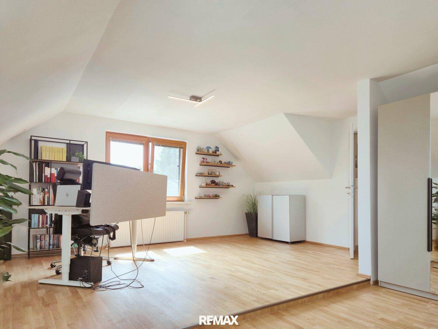 Geräumiges Büro im Dachgeschoss mit Holzboden, Dachschrägen und viel Tageslicht.