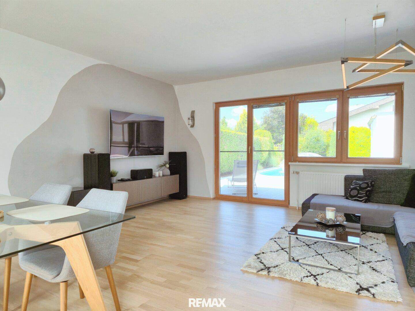 Helles Wohn-Esszimmer mit Holzboden, modernem Dekor und Zugang zur Terrasse mit Poolblick.