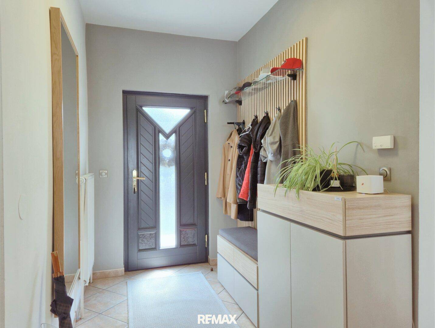 Heller Eingangsbereich mit Garderobe, Spiegel und Fliesenboden.