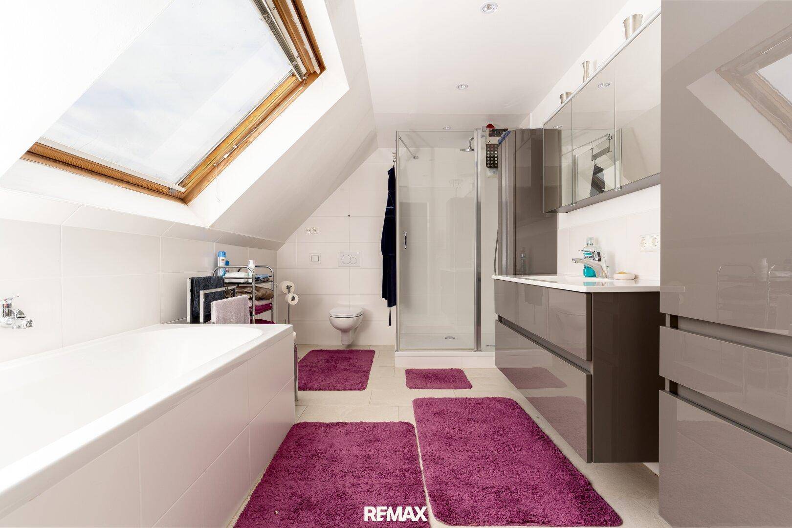 Helles Dachgeschossbad mit Badewanne, Dusche, modernem Waschtisch und großem Dachfenster.