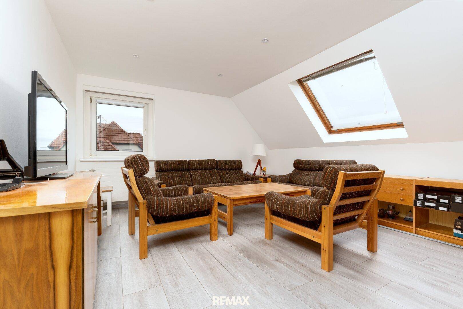 Gemütliches Wohnzimmer im Dachgeschoss mit bequemen Sofas, Fernseher und Dachfenster.